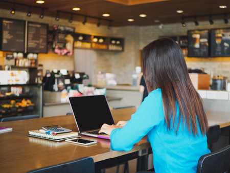 Pretty Young woman using laptop computer. Female working on laptop in an indoor cafe.の写真素材
