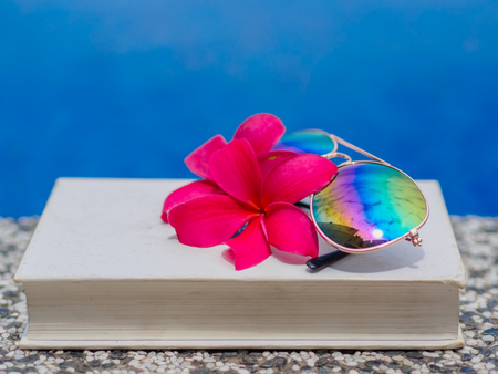 Book and sunglasses, blue water background, summer and tropical travel destinations conceptの写真素材