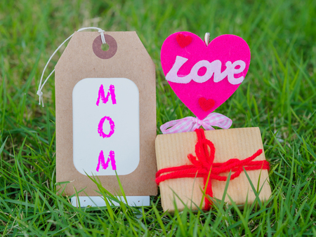 mother's day concept.  LOVE MOM text with colorful heart and gift on green grass backgroundの写真素材