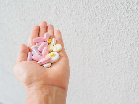 Medicine pills or capsules in hand, palm or fingers. Drug prescription for treatment medication. Pharmaceutical medicament, cure in container for health. Antibiotic, painkiller closeup.の写真素材