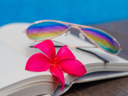 Book and sunglasses, blue water background, summer and tropical travel destinations conceptの写真素材