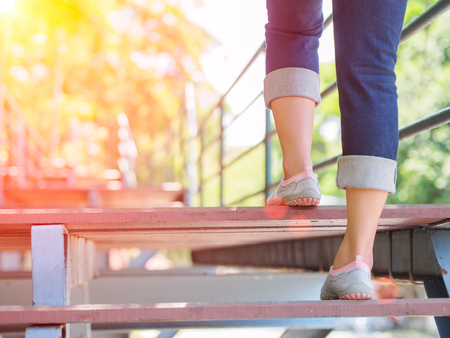 Pretty woman is stepping up a staircase with Lens Flare or sunspotの写真素材