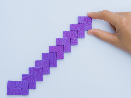 Concept of building success foundation. Women hand put puzzle wooden blocks in the shape of a...