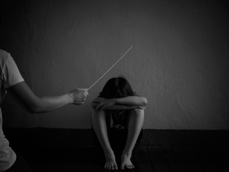 Domestic violence: female hand with belt on the background of kid. Abused child, aggression in the family.の写真素材