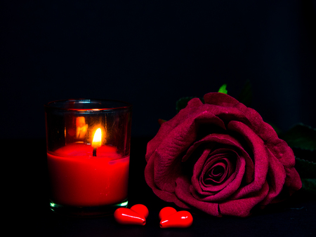 Low key of Valentines Day background-red rose with red candle and two red heartsの写真素材