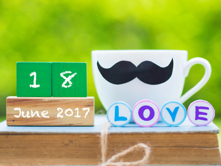 Father's day concept. stack of books, gifts, tea cup with black Mustache and flower on background