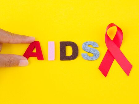 World AIDS day concept. red ribbon with hand holding AIDS text