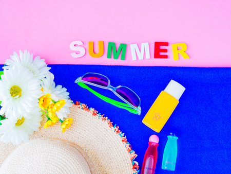 SUMMER alphabet with sunglasses, summer hat, sunscreen lotion, blue towel and flowers on pink...