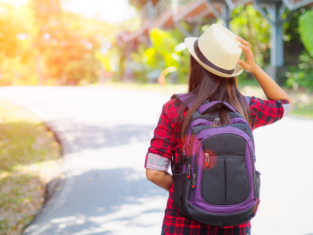 Happy Asian girl backpack in the road and forest background, Relax time on holiday concept travel.の写真素材