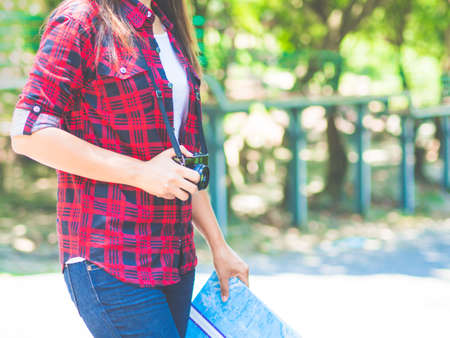 Happy Asian girl holding map with backpack in the road and forest background, Relax time on holiday concept travel ,color of vintage tone and soft focusの写真素材