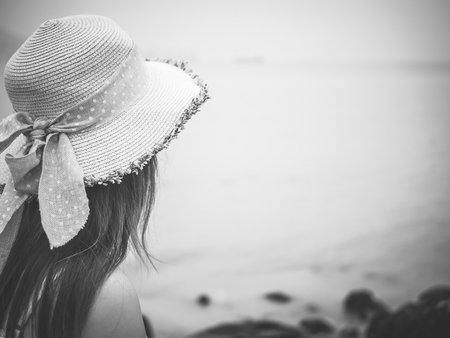 Black and white lonely and depressed woman standing in front of the sea in a deserted beach on an Autumn day.の写真素材