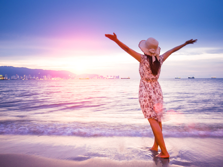 Strong confidence woman open arms under the sunrise at seaside. Summer and travel concept.の写真素材