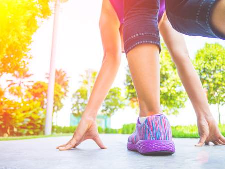 Ready steady go. Closeup of running shoes on grass, young lady on start position and going to run in...