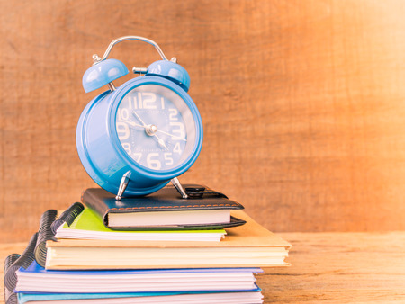 Back to school concept. Retro style of alarm clock on stacks of books with  wooden table background.の写真素材
