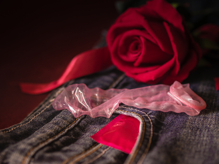 Low key of condom and red rose on pink background. Save sex , Family plan  and Valentine concept.の写真素材