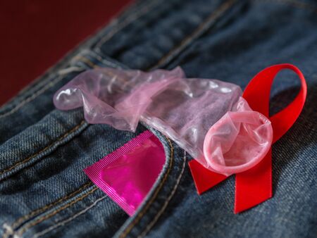 Low key of condom and red ribbon on jean background. Save sex , Family plan  and Valentine concept.の写真素材