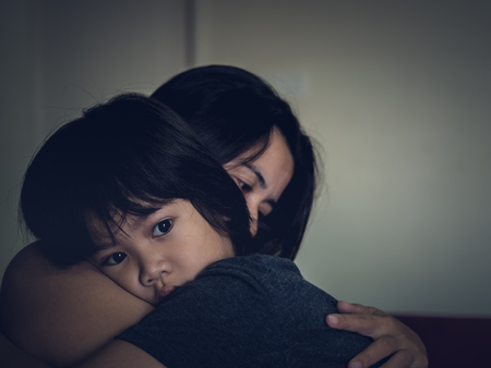 Mother and child, cute little boy resting on her mother's shoulder. Young mother holding her sad boy at home.の写真素材