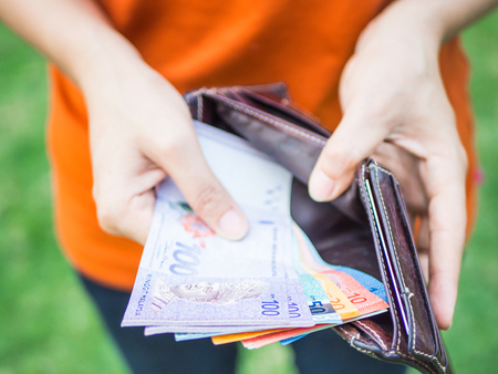 Closeup woman hand putting money into leather wallet . Business and financial, money saving concept.の写真素材