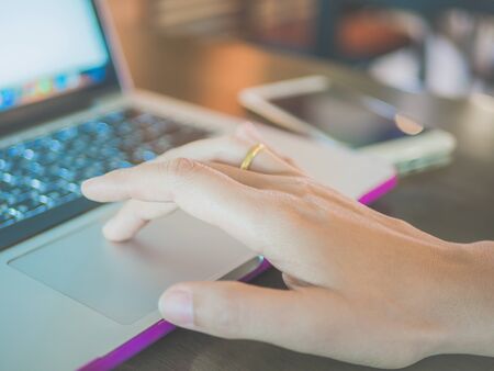Closeup of woman hand at cafe working on her laptop computer. Business finance and education concept.の写真素材