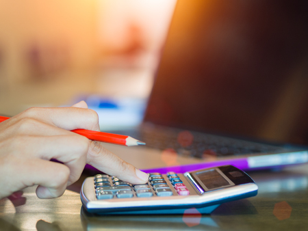 Woman working with calculator, business document and laptop computer notebookの写真素材