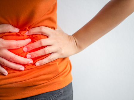 Young beautiful woman having painful stomachache.Chronic gastritis. Abdomen bloating concept.の写真素材