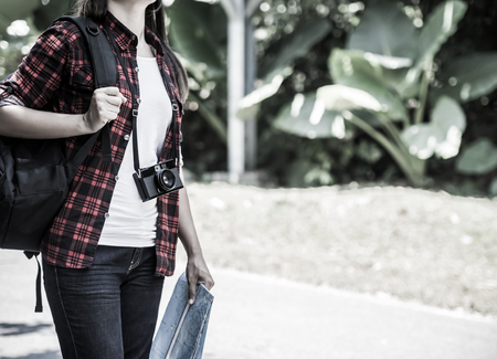 Retro style of asian girl holding map with backpack in the road and forest background, Relax time on holiday concept travel.の写真素材