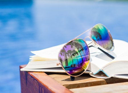 Closeup sunglasses and book at the side of swimming pool. Vacation, beach, summer travel conceptの写真素材
