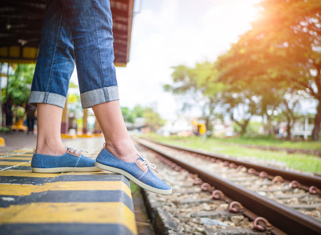 Closeup young girl tourism danger walking step is falling to railway at train station platform.の写真素材