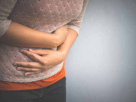Young woman having painful  stomachache. Chronic gastritis. Abdomen bloating concept.の写真素材