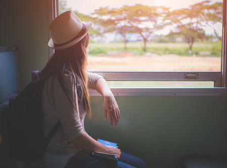 Young pretty woman traveling by the classic train sitting near the window looking outside. Vacation...