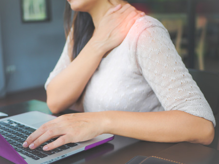 Closeup woman with hands holding her shoulder pain. Office syndrome and Health-care Concept.の写真素材