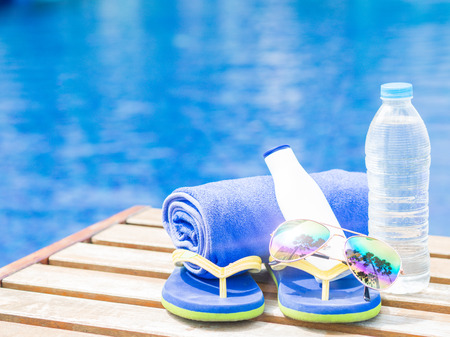 flip flops, sunglasses, blue towel and sunscreen at the side of swimming pool. Vacation, beach, summer travel conceptの写真素材