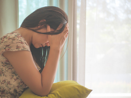 Closeup depressed woman crying while sitting alone on the floor. Sad woman concept.の写真素材