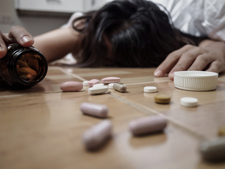 Young woman is lying on the floor with a lot of pills. Overdose and concept.の写真素材