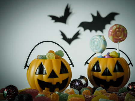Trick or treat halloween bucket filled with colorful candies on white backgroundの写真素材