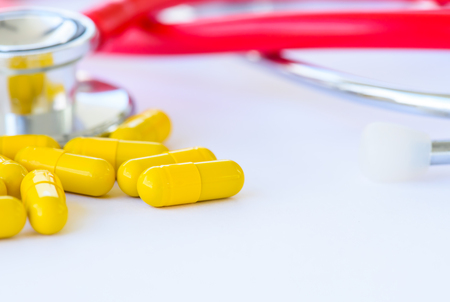 Closeup yellow pills, capsule with stethoscope background.  Medical and health care concept.の写真素材