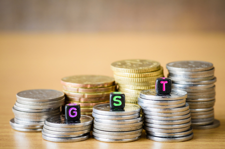 GST Concept with alphabet block on a gold stacked of coins.の写真素材