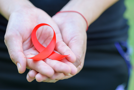 Woman hands holding red AIDS awareness ribbon. Aids Awareness campaignの写真素材