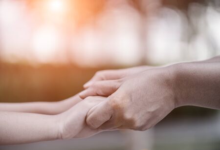Mother holding a hand of his son with green glass background. Love , famiy and mother day concept.
