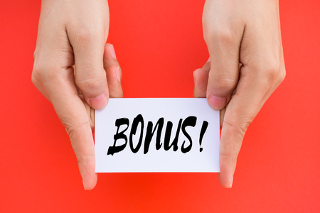 Hand holding Bonus card with red background. Business achievement concept.の写真素材