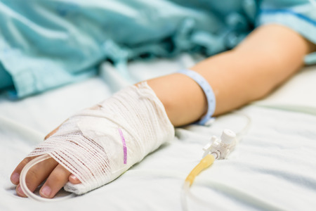 Closeup kid hand  sleeps on a bed in hospital with saline intravenous.の写真素材