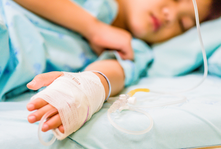 Closeup kid hand  sleeps on a bed in hospital with saline intravenous.の写真素材