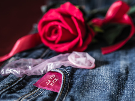 Low key of condom and red rose on blue jean background. Save sex  and Valentine concept.の写真素材