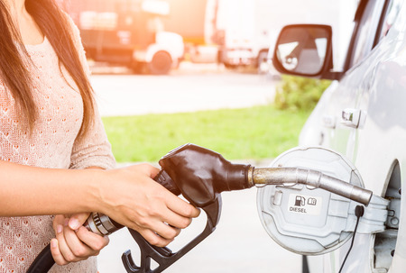 Woman pumping gasoline fuel in car at gas station.の写真素材