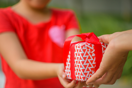 Mother hand giving a gift box to her child.  Holidays, present, christmas, childhood and happiness conceptの写真素材