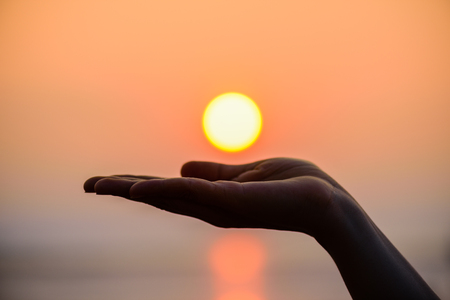 Close up and Silhouette of hand holding sun. Sun on woman hand.の写真素材