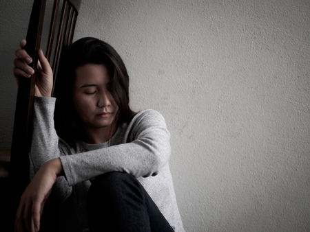 Depressed broken hearted woman sitting alone in dark room at home. Lonly , sad, LOVE and  valentines day concept.の写真素材