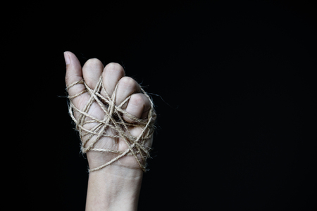a woman hand tied with wire on dark background in low key. international human rights day concept.の写真素材