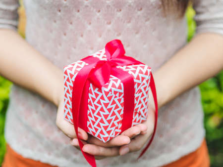 Female hand holding a gift box with red ribbon.  Love, valentine, christmas and new year concept.の写真素材