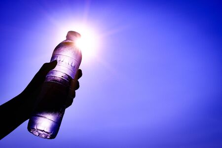 Silhouette of closeup Woman's hand holding plastic water bottle over sunlight effect. World Water Day concept.の写真素材